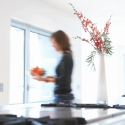 Woman walking in kitchen of her house.