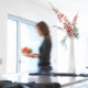 Woman walking in kitchen of her house.